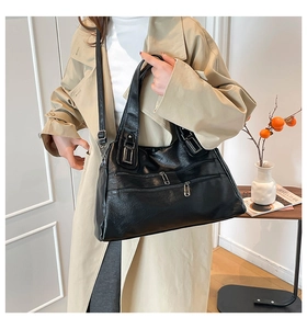 Detail of black vintage faux leather tote with functional silver zippers and crossbody strap