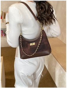 Detail of dark brown canvas tote bag with gold chain strap and stylish leather trim details