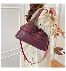 Side view of a burgundy leather tote bag with dual front zippers and a slender shoulder strap