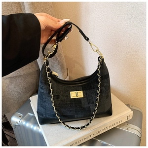 Detail of grey tweed tote bag featuring golden turn-lock closure and woven chain strap