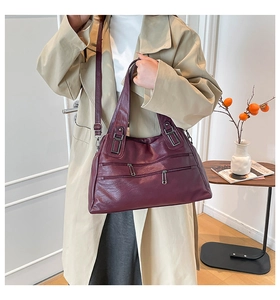 Detail of burgundy PU leather bag with multiple zippers and adjustable shoulder strap