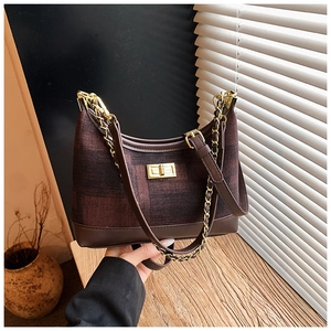 Macro detail of brown checkered fabric texture and golden metal twist lock on the tote bag
