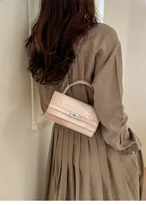 Detailansicht der Handtasche mit Krokodilmuster und silberner Kette am Kleid