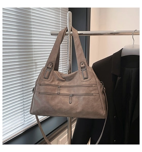 Detailed view of the double metal zipper pockets and grainy faux leather of the taupe bag