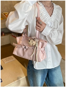 Détail du sac à bandoulière rose brillant avec un charm d'ours en peluche sur modèle