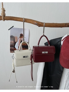 Detail von Vintage-Umhängetaschen in Creme und Burgund mit Metall-Drehverschluss-Detail