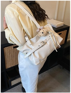 Détail du sac cabas blanc brillant avec boucles métalliques et un joli pendentif ours en peluche