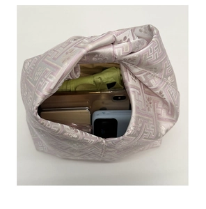 Vue détaillée de l'intérieur d'une pochette rose jacquard avec téléphone et objets