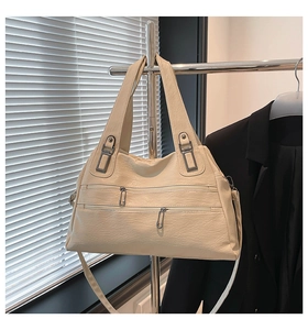 Detail of cream faux leather shoulder bag with multi-layer zippers on a metal stand