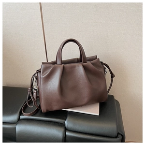 Dettaglio della trama a pieghe marrone scuro e dei manici in pelle della borsa elegante