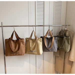 Row of canvas tote bags in brown, beige, grey and olive colors on metal hanger