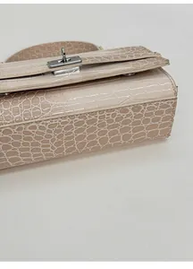 Detailansicht des breiten Bodens der beigefarbenen Handtasche mit Krokoprägung