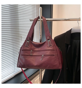 Close-up of wine red leather handbag featuring dual zippers and silver metal hardware accents