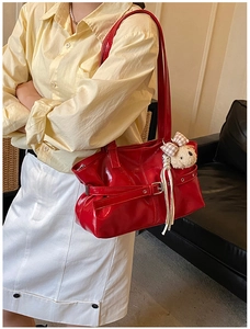 Détail du sac à bandoulière rouge brillant avec boucle et charm ours sur un modèle