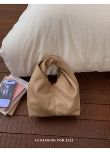 Detail of camel cloud bag featuring artistic knotted handle and pleated texture design