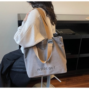 Detail view of large grey canvas tote bag with brown straps and INSIDE OUT print