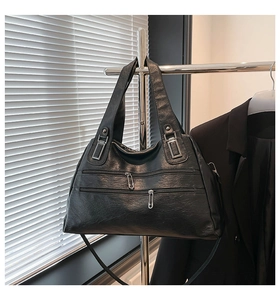 Close-up of black PU leather tote bag with silver pin zippers and multi-pocket details