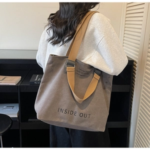 Detailed shot of large canvas tote bag with wide brown straps and artistic text print