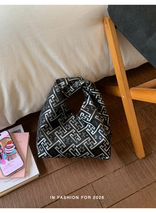 Detail of black jacquard handbag featuring silver geometric patterns and knotted handle