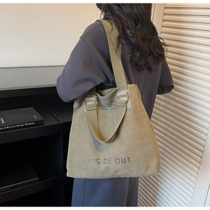 Detail showing the heavy olive green canvas tote bag with INSIDE OUT text on wide strap