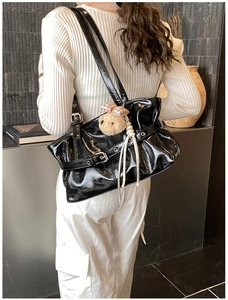 Détail du sac à bandoulière noir brillant avec design plissé et breloque ours en peluche