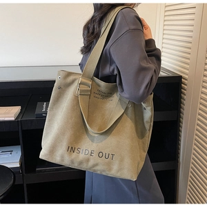 Close-up of olive green canvas tote bag with Inside Out print and metal rivet details