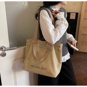 Detail view of the khaki canvas tote bag showing the letter print and large capacity