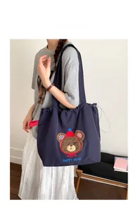 Detail of navy canvas tote bag featuring brown party bear embroidery and large capacity