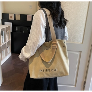 Detail of a large beige canvas tote bag with Inside Out print and dual handle design