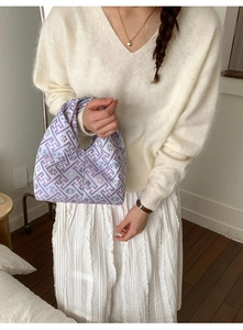 Détail d'un sac à main brodé lilas porté avec un pull en maille blanc élégant