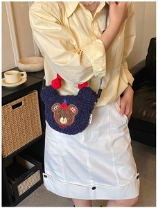 Deep blue plush bear crossbody bag shown in a cozy lifestyle setting on a sofa