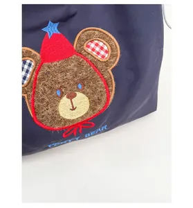 Close-up of navy blue tote bag featuring detailed 3D plush party bear embroidery and text