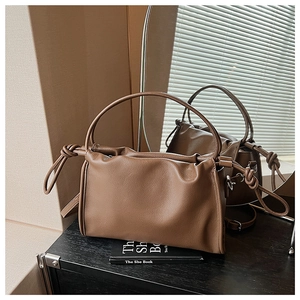 Détail de la texture cuir litchi marron caramel et nœud latéral sur le sac nuage