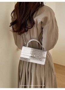 Detail der weiß-braunen Kroko-Handtasche mit Silberkette und Metall-Drehverschluss