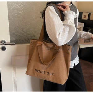 Detail of large brown canvas tote bag with INSIDE OUT print and reinforced straps