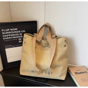 Detail shot of khaki canvas tote bag showing reinforced rivets and sturdy shoulder straps