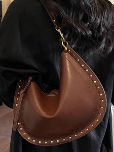 Brown leather shoulder bag with gold studs and asymmetrical curved design for women