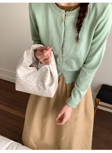 Détail du sac à main blanc cassé orné de motifs géométriques dorés et de fleurs fines