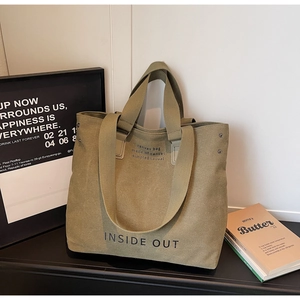 Detail of army green canvas tote bag showing reinforced rivets and casual print