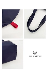 Detail view of the durable navy blue canvas tote bag showing the handles and red accents
