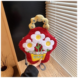 Close-up of cute red plush flower crossbody bag with rich embroidery on wooden table