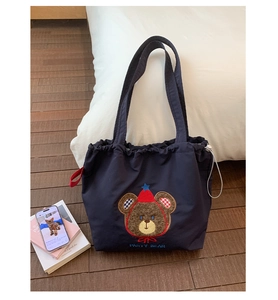 Close-up of navy canvas tote bag featuring brown party bear embroidery and drawstring closure