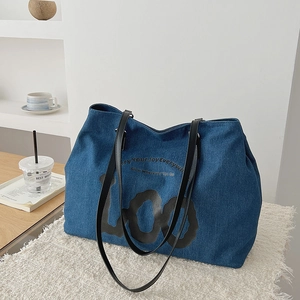 Detail of dark blue denim tote bag with black LOO lettering and thin leather shoulder straps