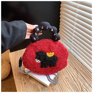 Close-up of red plush bag with cartoon cow embroidery and woven crossbody strap