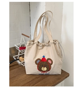 Detail of embroidered party bear on cream canvas tote bag with drawstring closure