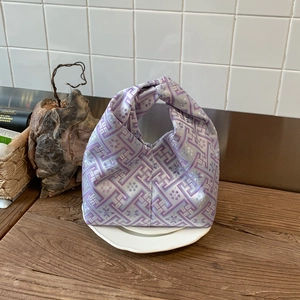 Detail of lavender silk brocade handbag with plum blossoms on a white ceramic plate