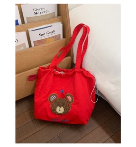 Close-up of red canvas tote bag with cute bear embroidery and drawstring closure