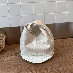 Close-up of champagne knot handle bag with geometric patterns on a decorative plate