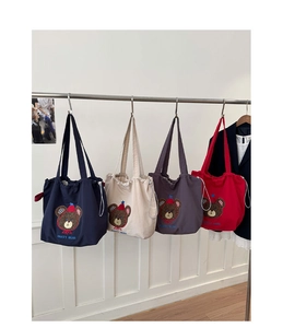 Detail of four colorful canvas tote bags with bear embroidery and drawstring closure