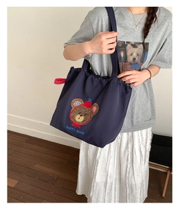 Close-up of navy canvas tote bag featuring a cute embroidered party bear patch